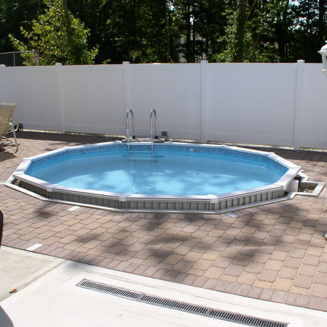 An 18' x 52" SPD Aquasports Aluminum Panel Semi-Inground Round Combo Pool is installed in a paved patio area, enclosed by a white privacy fence with trees visible in the background.
