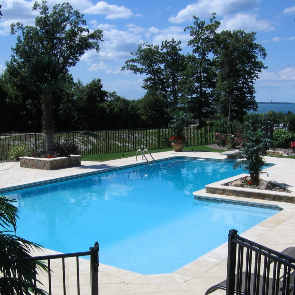 The SPD 20' x 40' Discount Super Steel Inground Pool Kit features a rectangular design with clear blue water, a tiled patio, potted plants, and black metal fencing. Enjoy lasting steel quality with trees and lake views beneath a blue sky.