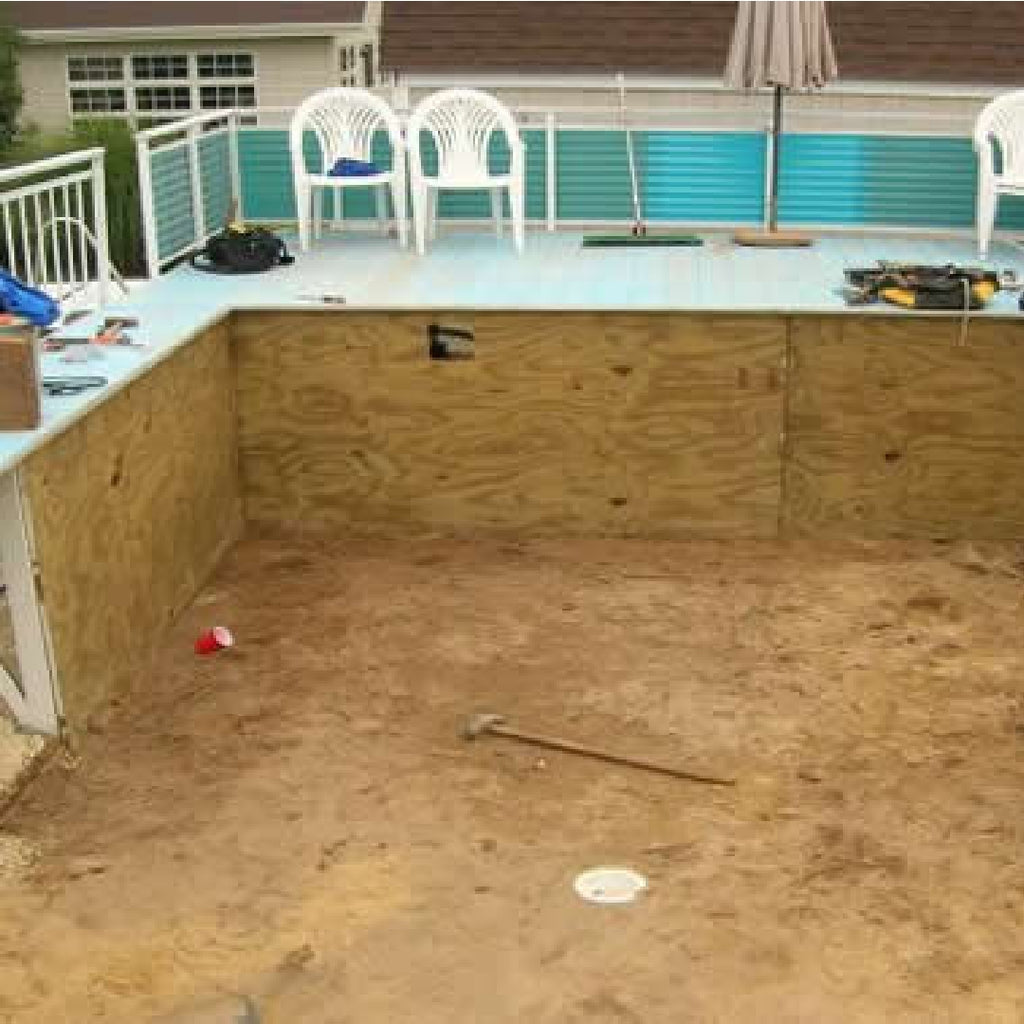 A 48" Perma 25 Fanta Sea - Kayak Mystri Gold Full Print Rectangular Beaded Liner from SwimmingPoolDiscounters being installed in a backyard pool with plywood walls and a dirt floor, surrounded by tools, white chairs, and a patio umbrella.