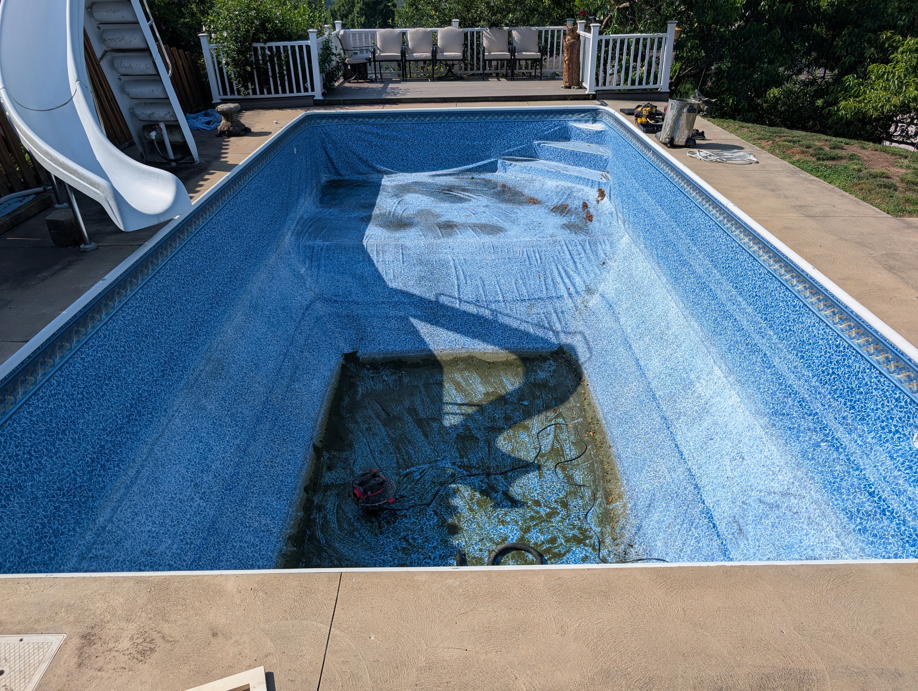 In-ground pool with a slide and deck area in the background