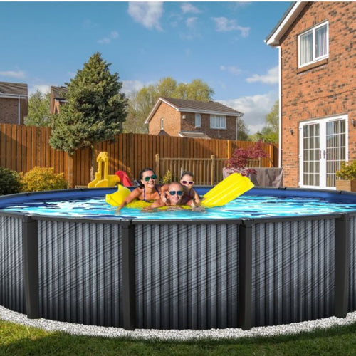 Four kids in sunglasses play in the Swimming Pool Discounters 24' x 54" Round Above Ground Resin Downtowner Pool with Light, set beside a brick house and wooden fence, with green trees and nearby homes in the background.