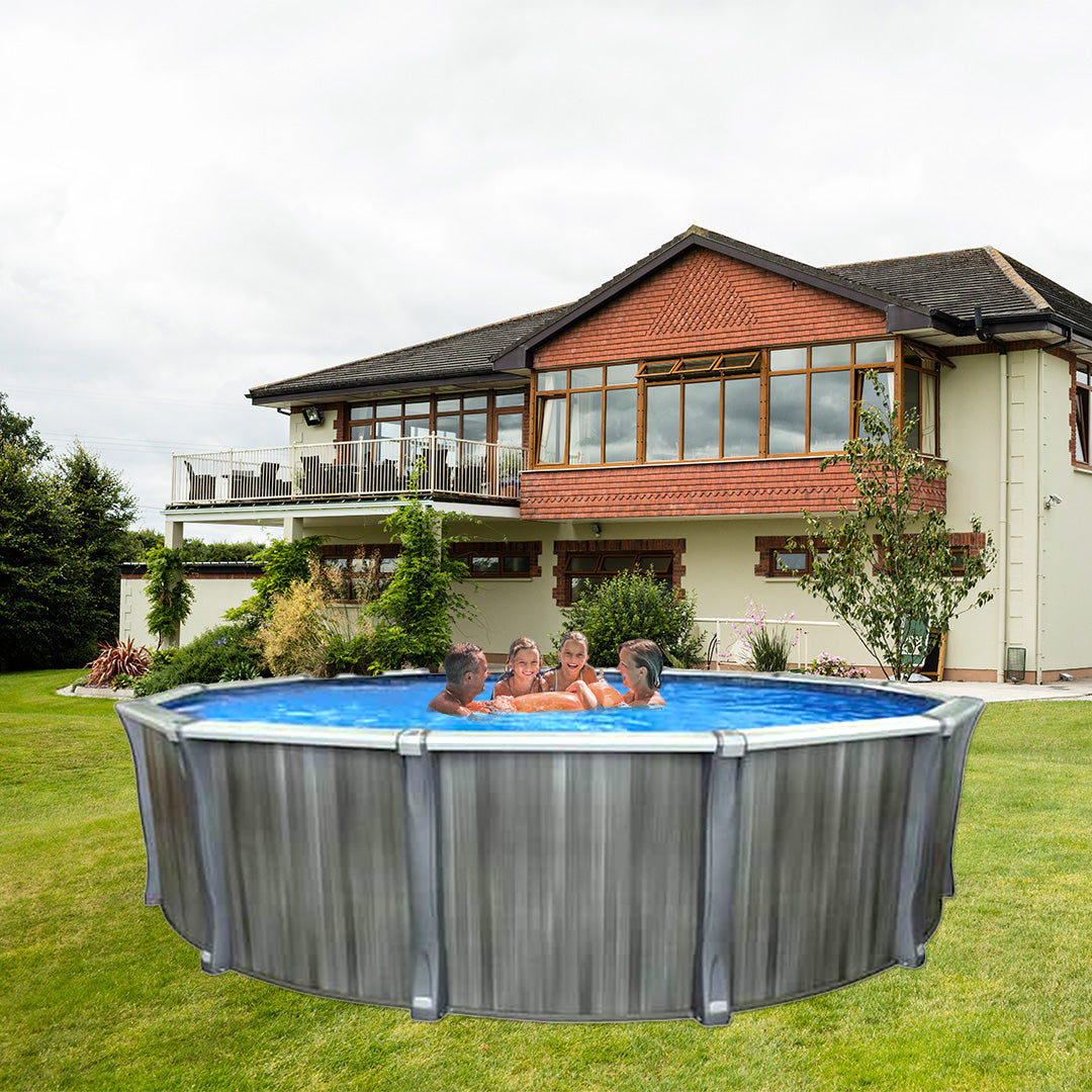 Four people relax and chat in a Trevi 211 27' x 52" Resin Frame Round Pool by Trevi, set on the green lawn of a modern house with large windows and a balcony in the background.