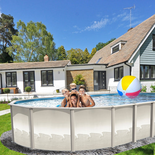 Four smiling children play in an SPD 15' x 30' x 54" Resin Guard Hybrid Salt Oval Pool by a modern house on a sunny day. A colorful beach ball soars above the rust-resistant pool, with trees and green grass in the background.
